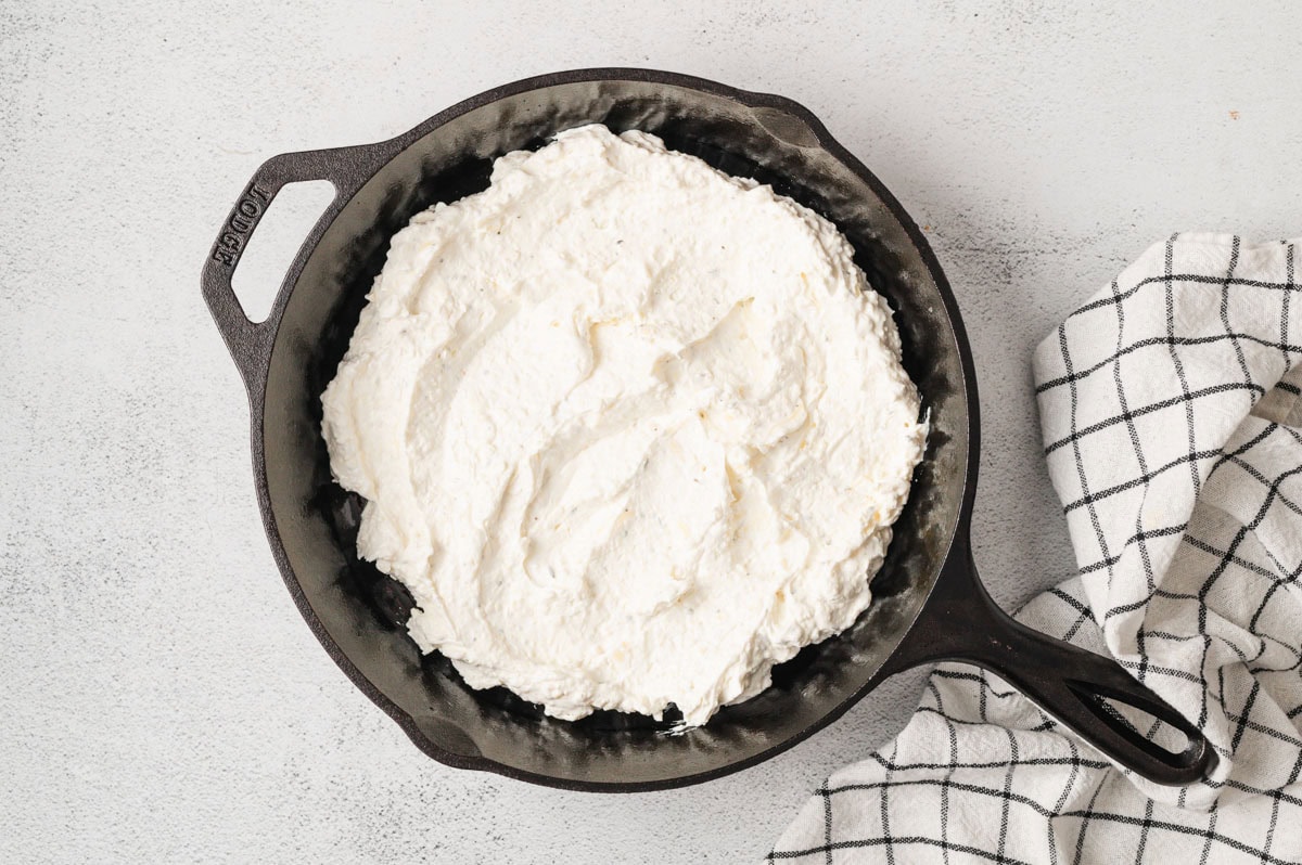 Cream cheese, sour cream, garlic, Italian seasoning in a cast iron pan.