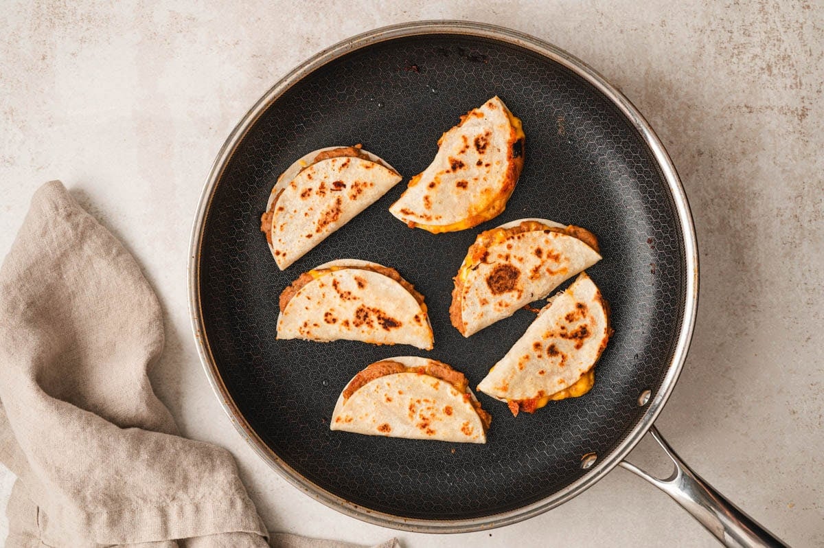 6 mini quesadillas cooking in a skillet
