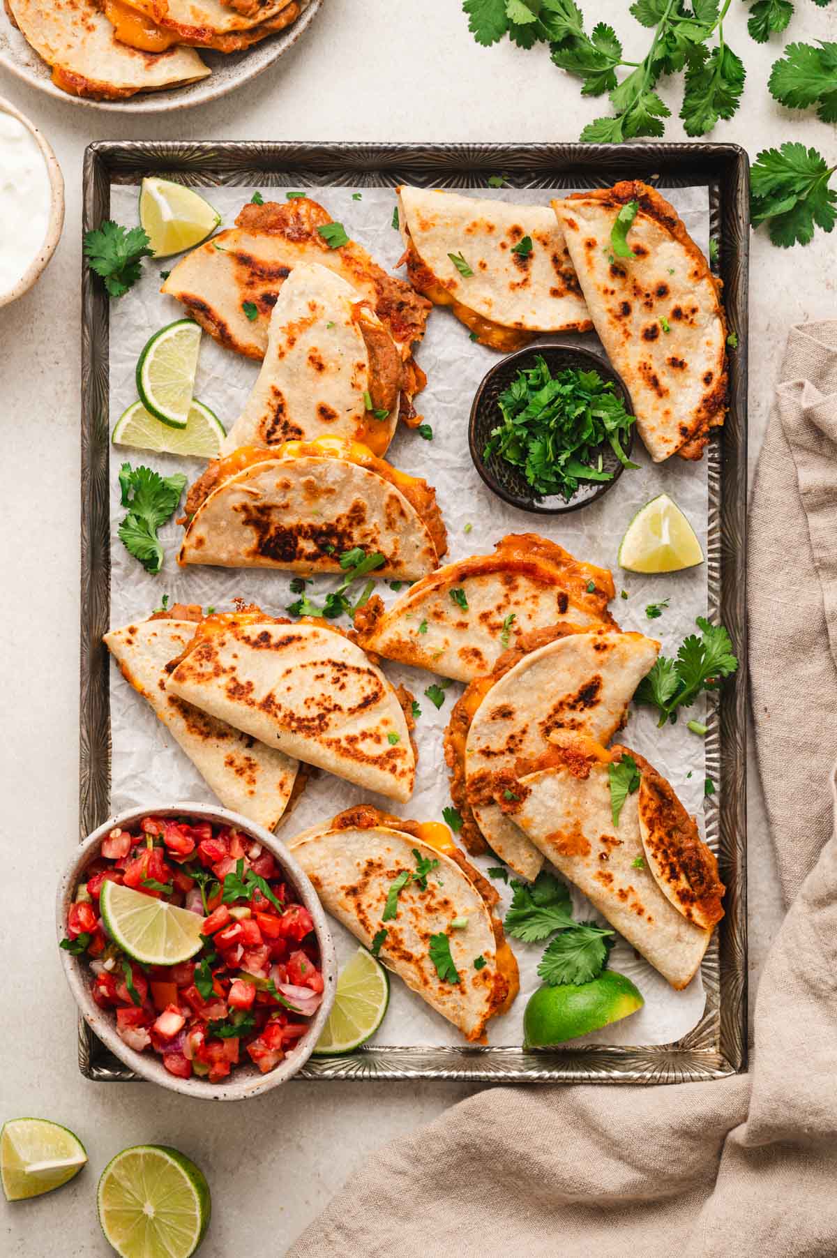 mini quesadillas on a pan garnished with cilantro, salsa, and lime wedges