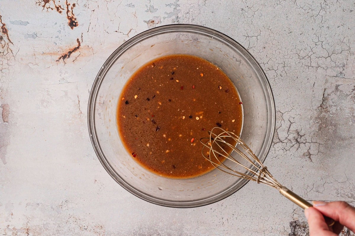Sauce in glass bowl with wire whisk