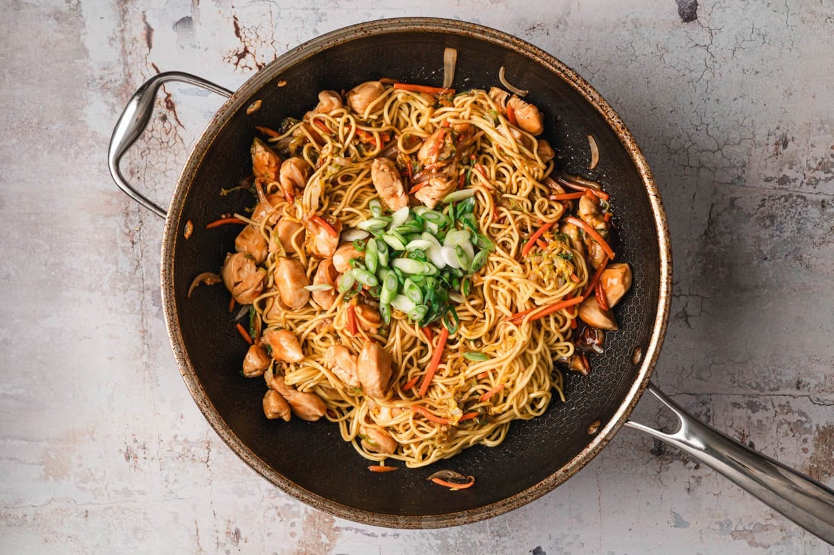 chicken, veggies, sauce, noodles, and green onions in saute pan