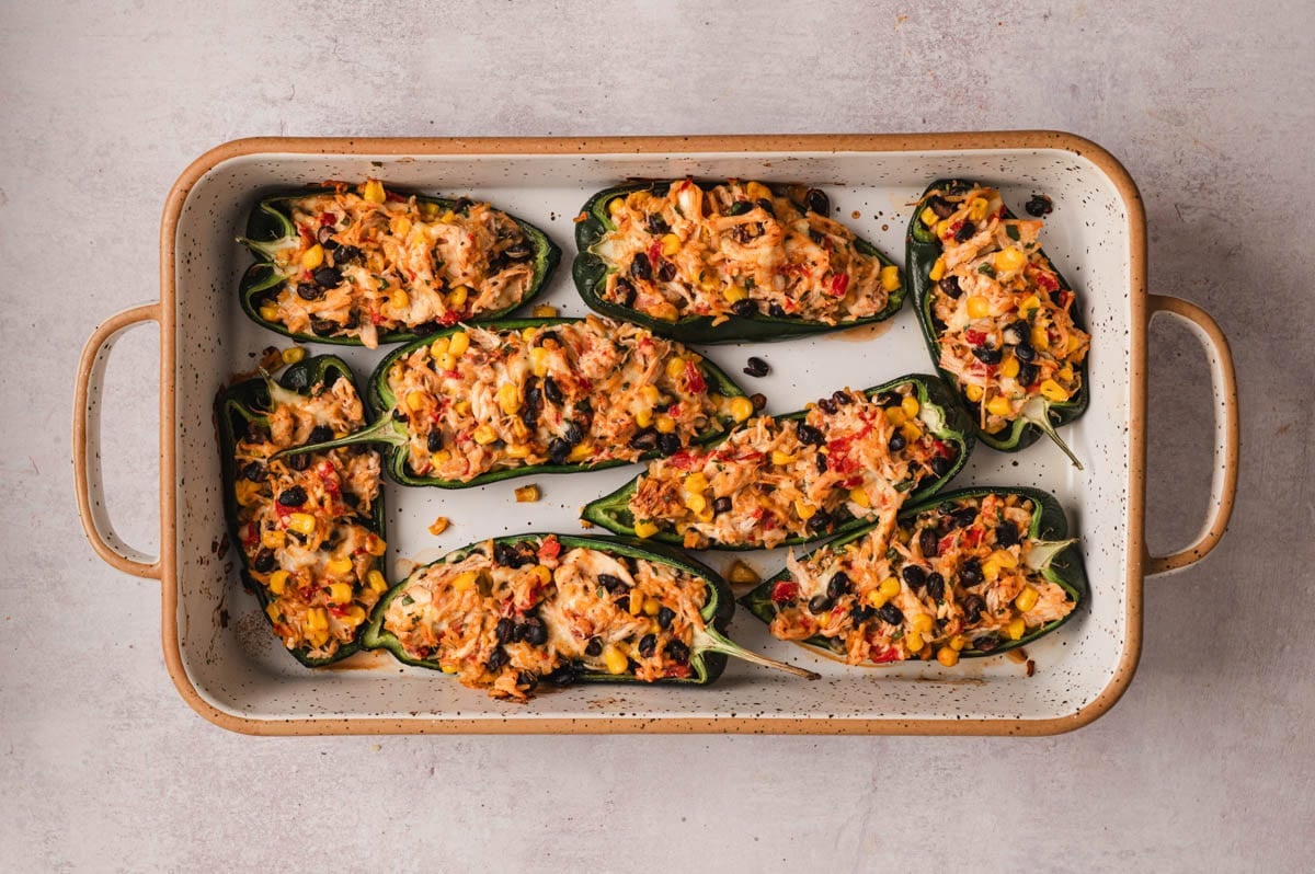 Baked stuffed poblano peppers in a baking dish.