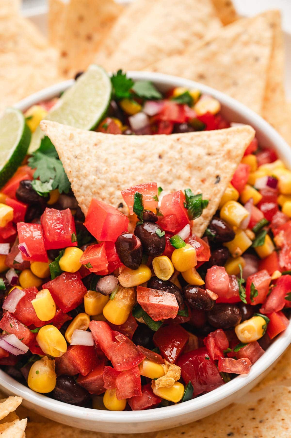 Overhead photo of corn and black bean salsa in a white bowl with tortilla chips.