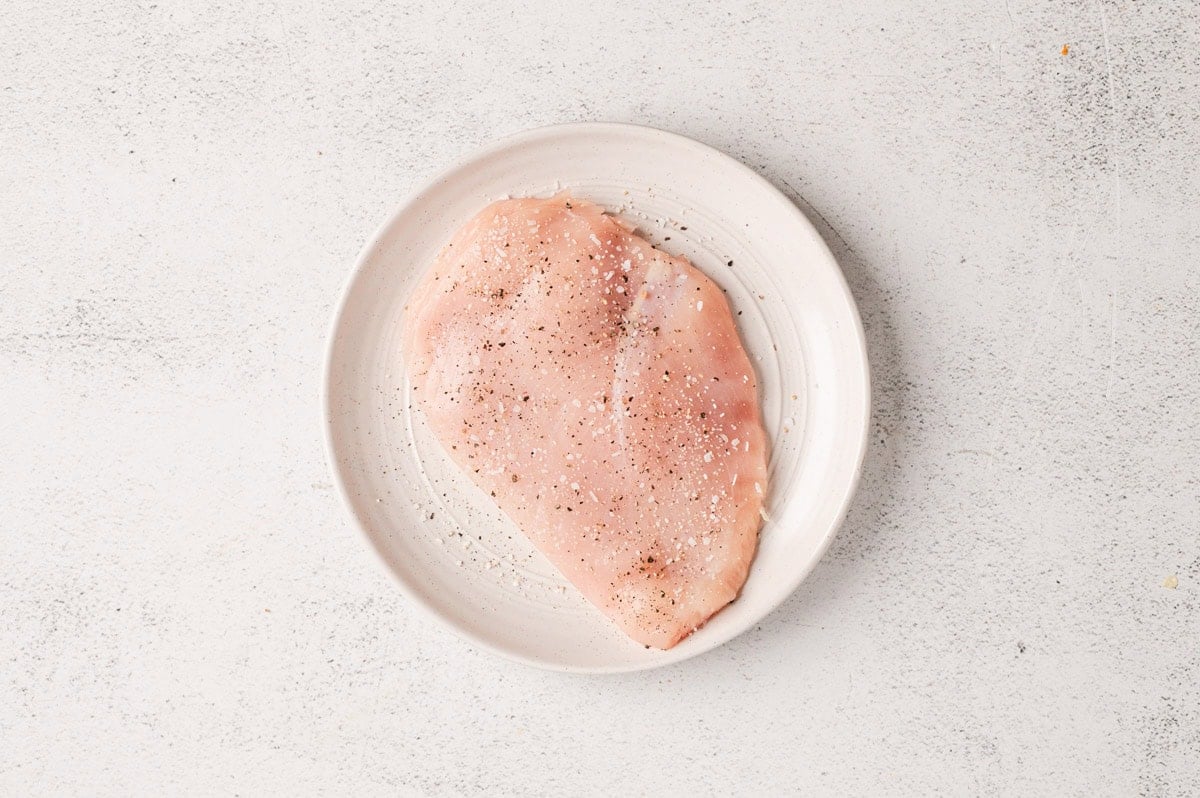 Raw chicken cutlet on a white plate