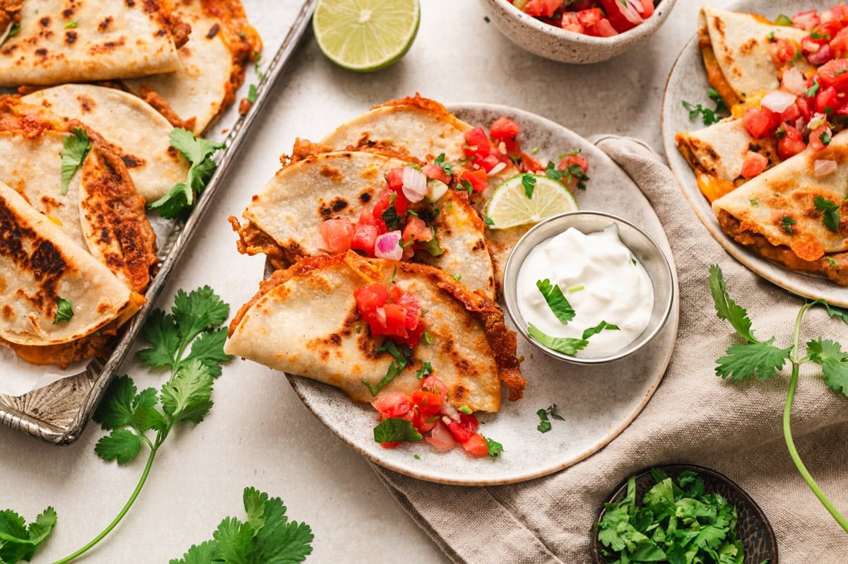 mini quesadillas garnished with pico de gallo, sour cream, cilantro and a lime wedge