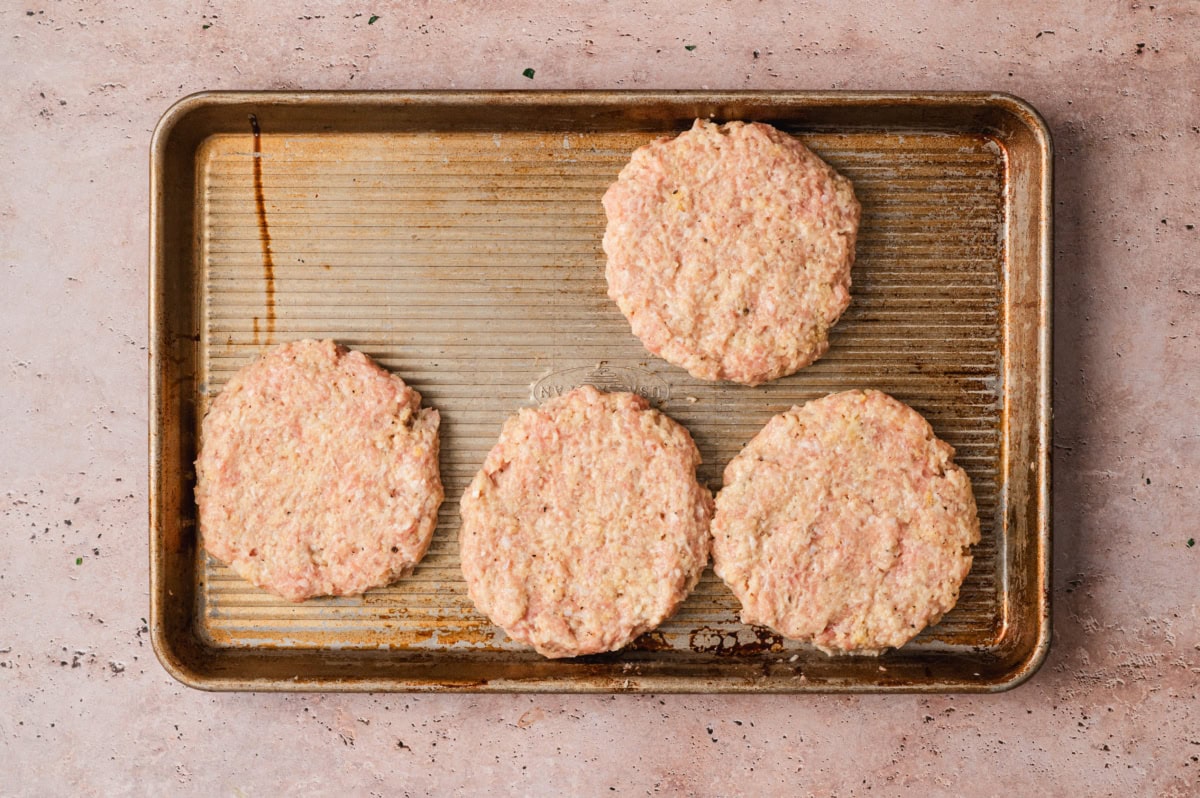 Ground chicken burger patties on a sheet pan.