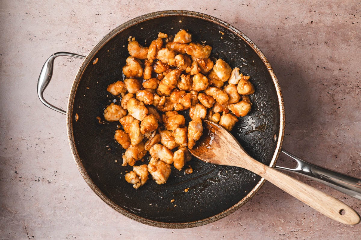 Cooked chicken pieces in sauce in a saute pan.