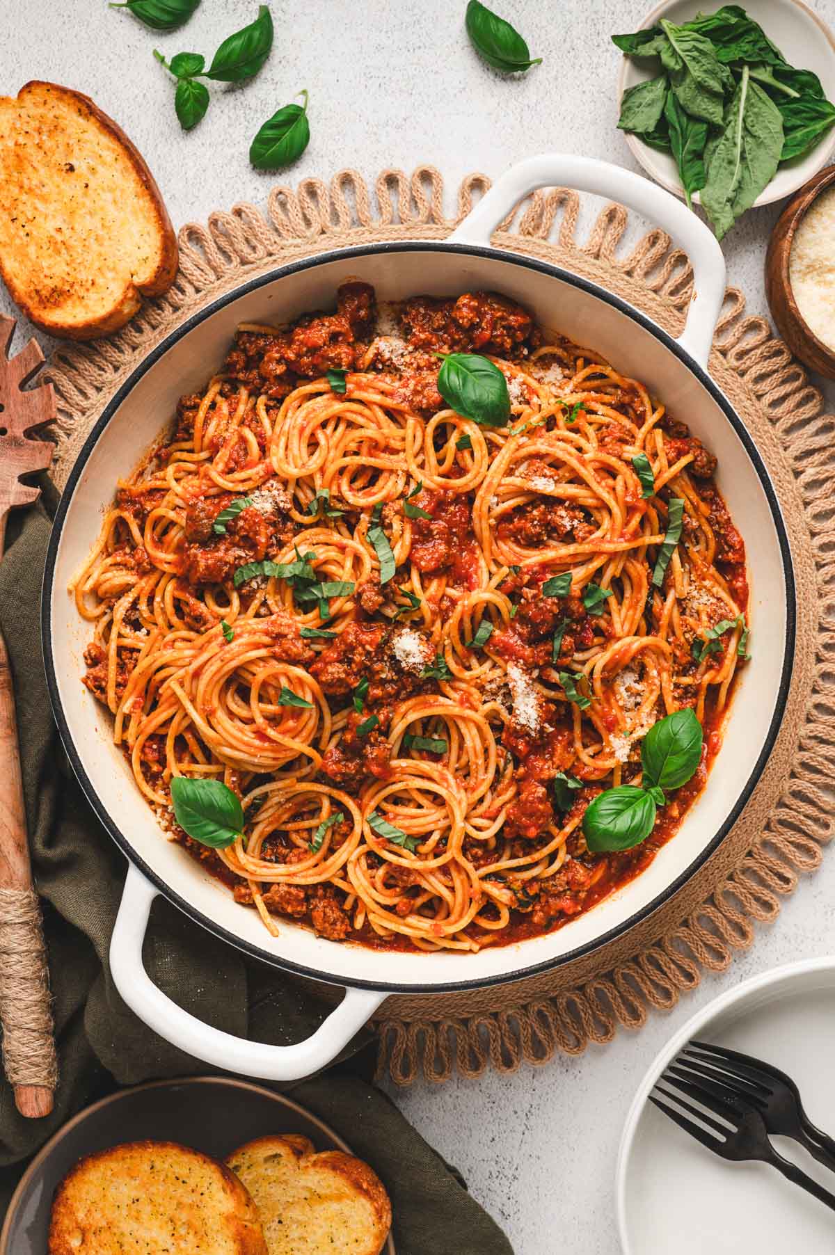 Spaghettie with meat sauce and fresh basil in a white serving dish.