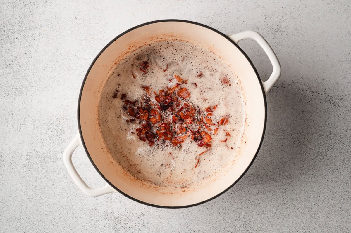 Bacon cooking in a white enameled pot