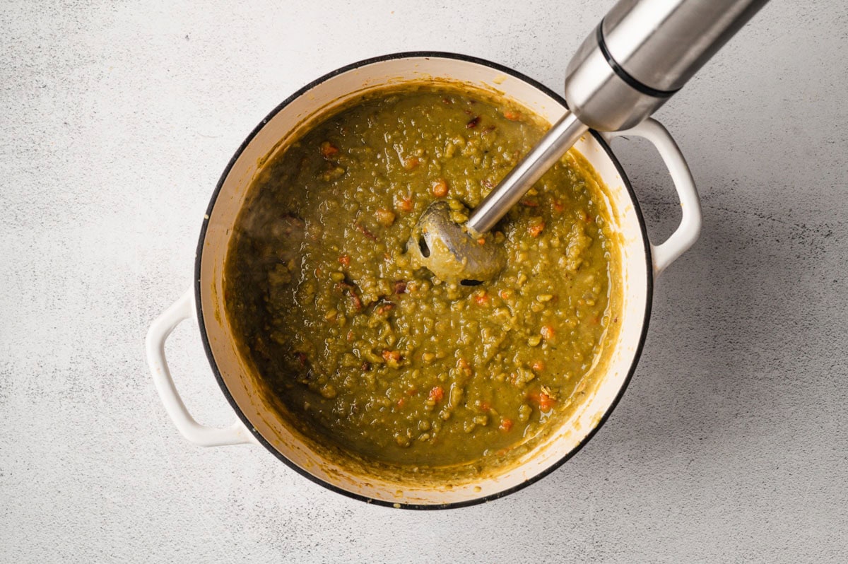 Split pea soup in a white enameled pot and immersion blender