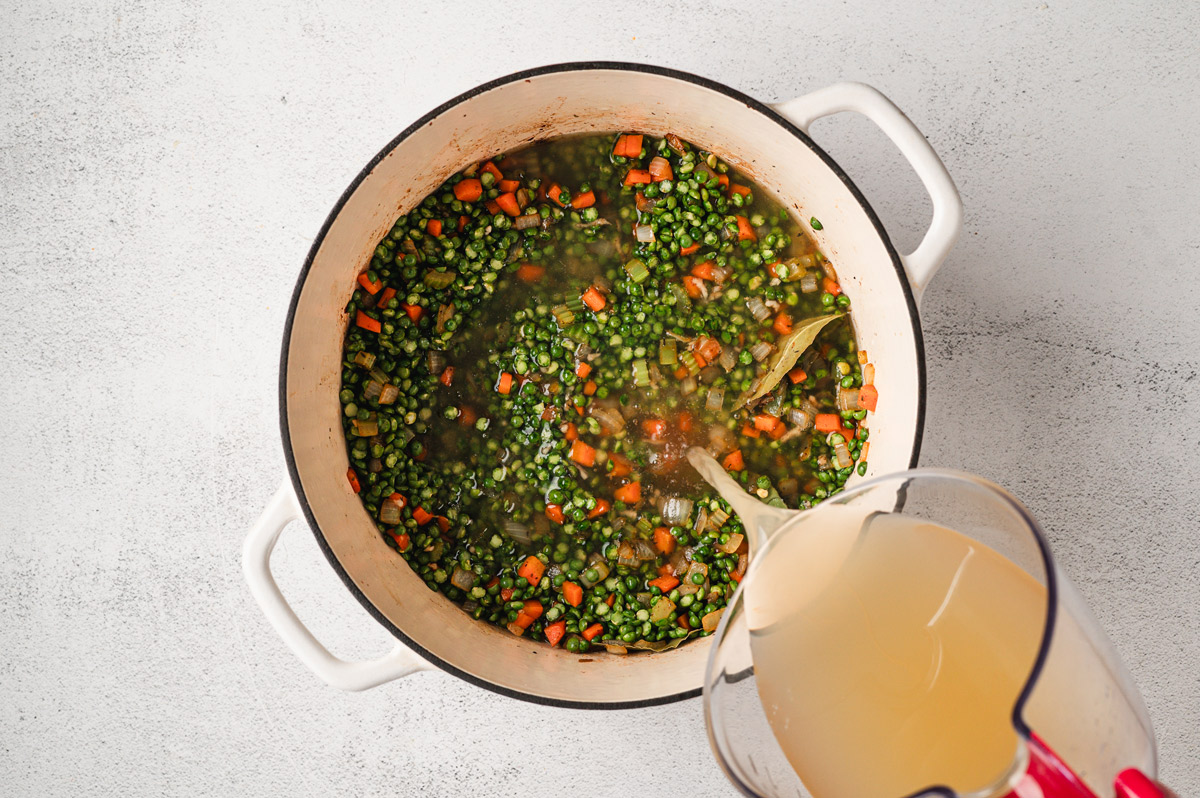 Ingredients for split pea soup in a white enameled pot