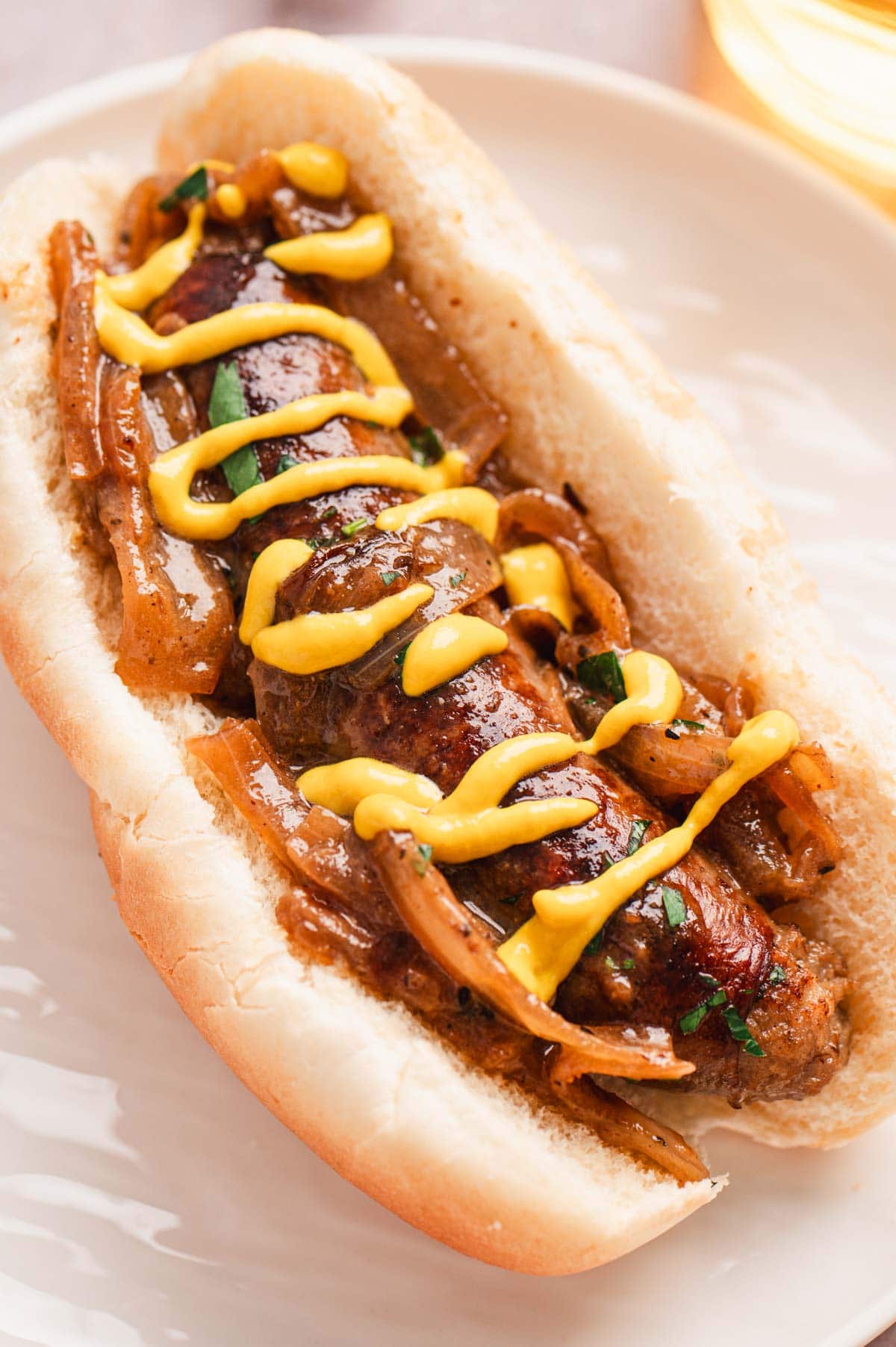 Bratwurst sausage with onions in a bun topped with mustard.