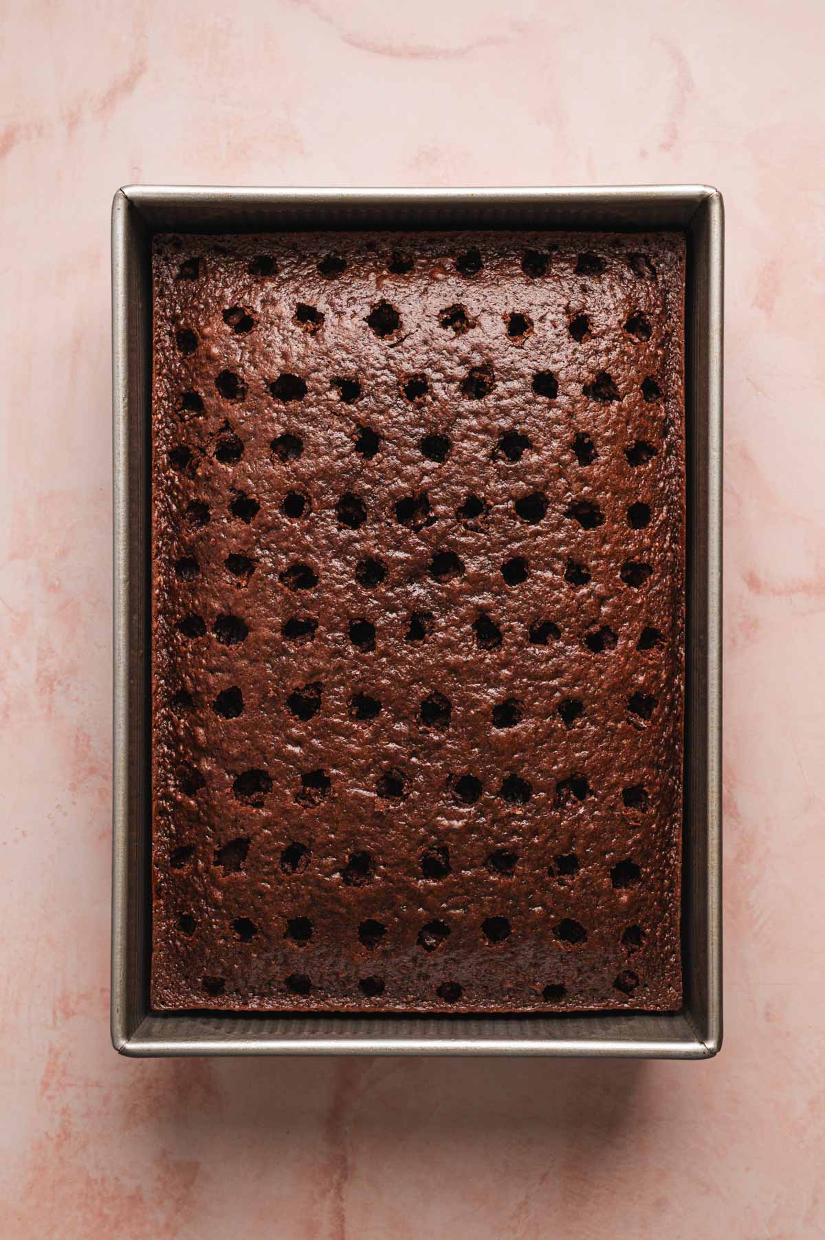 Chocolate cake in a pan with holes poked in it.