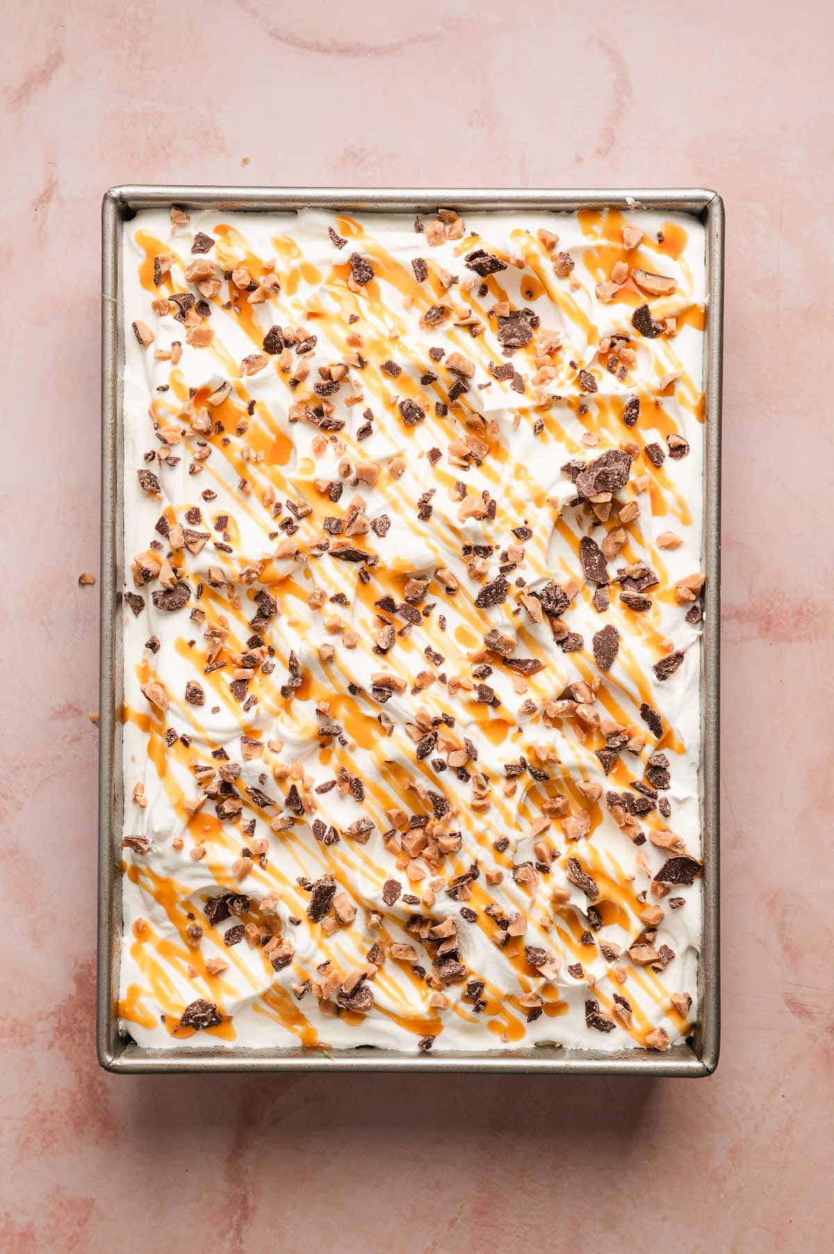 Better than sex cake topped with whipped topping, caramel sauce, and candy bar pieces.