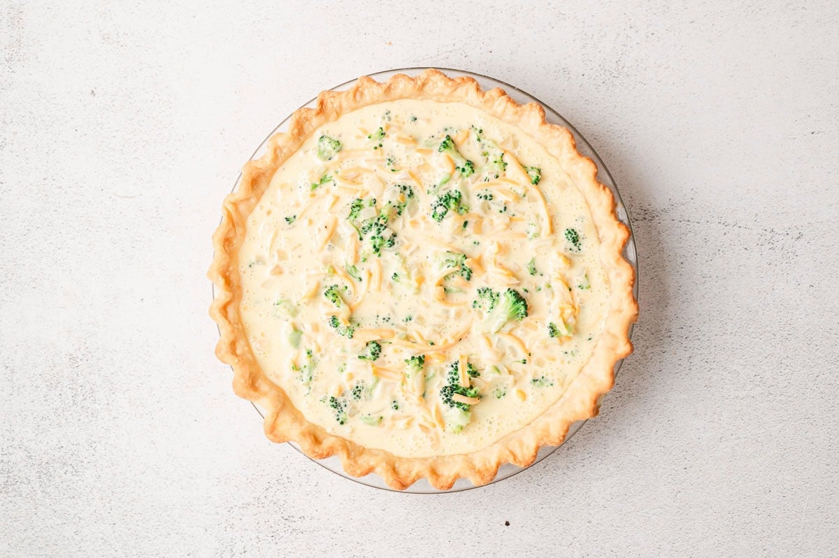 Uncooked broccoli cheddar quiche in pie crust.