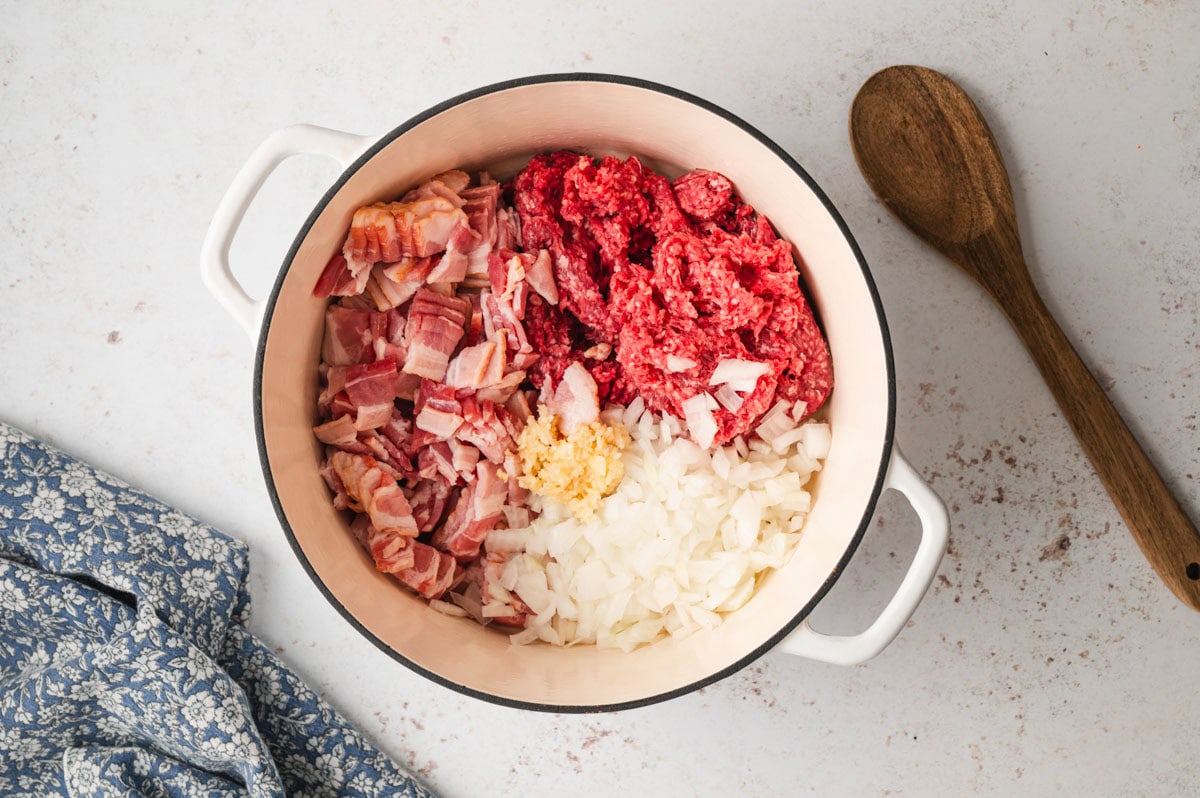 Dutch oven with bacon, ground beef, onion, and spices.