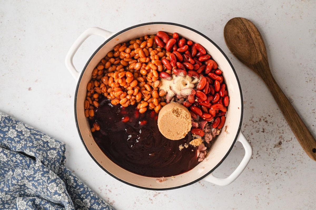 Dutch oven with beans, brown sugar, BBQ sauce, and spices.