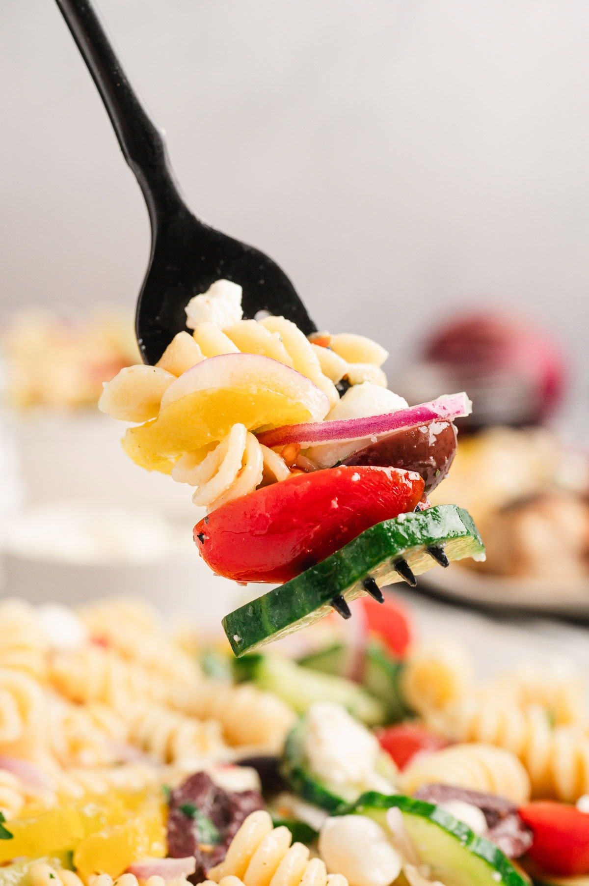 Close up of a bite of pasta salad on a black fork.