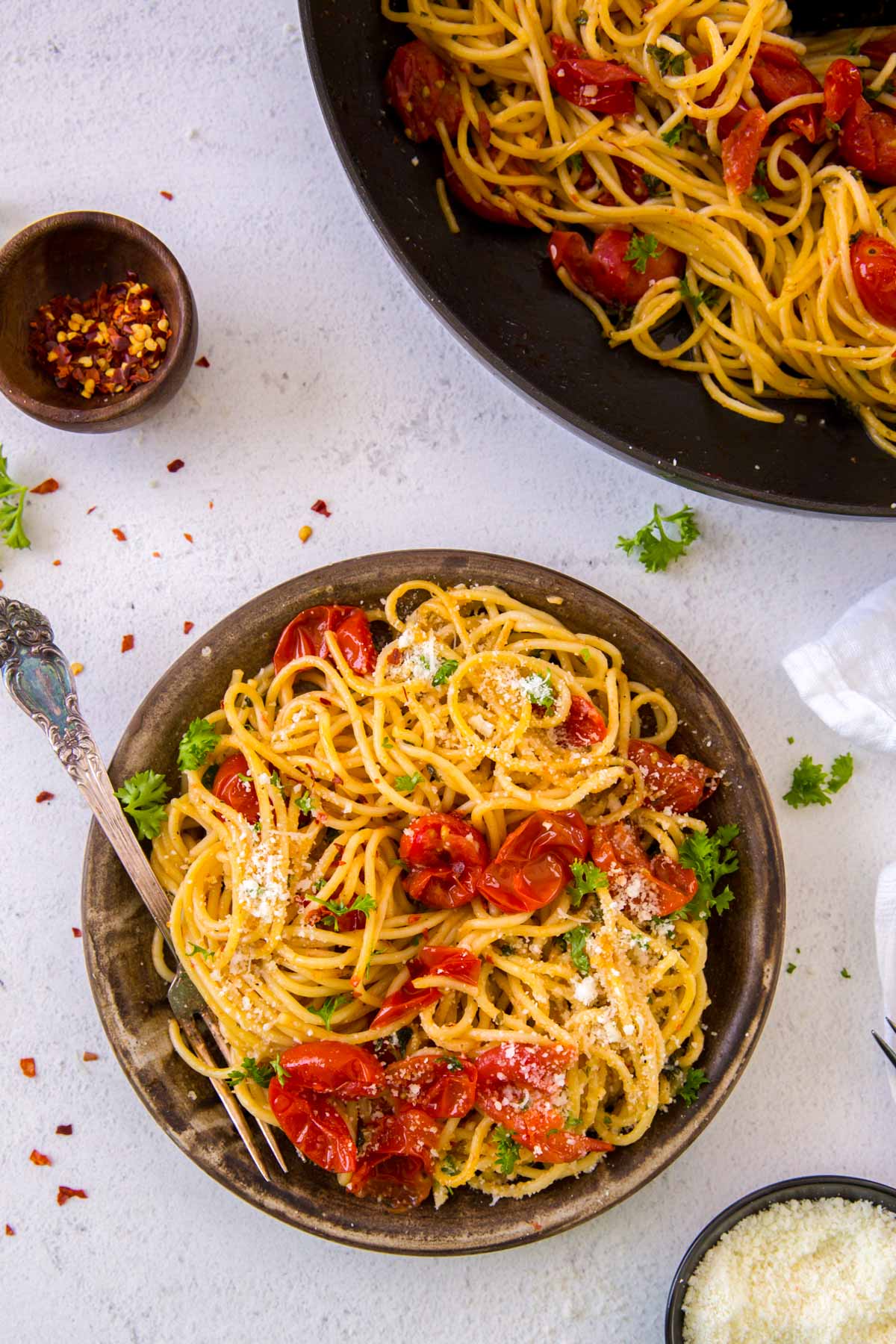 Garlic and tomato pasta in a large stone serving bowl garnished with parsley.