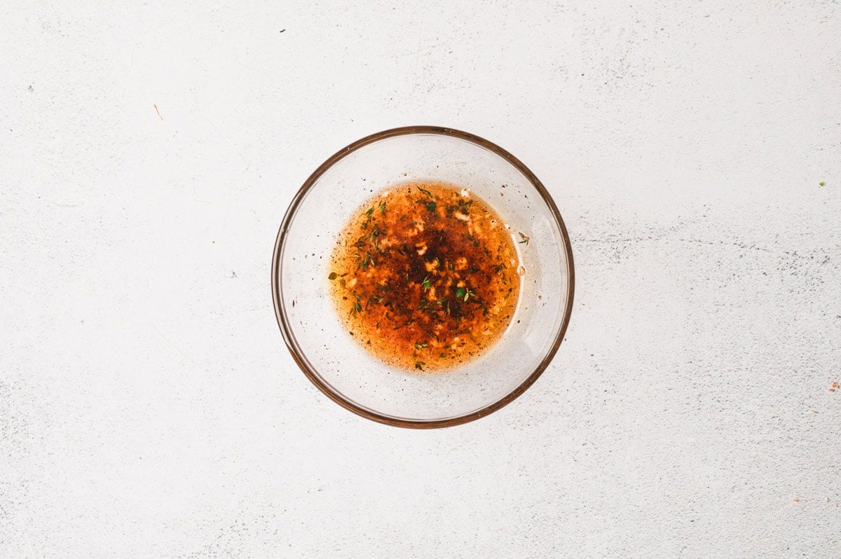 The seasoned oil mixture for Grilled Vegetables in a glass bowl.