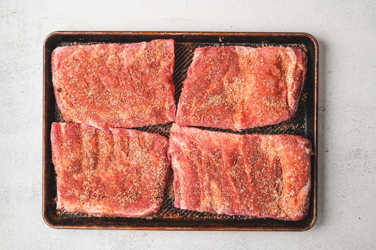 St. Louis Ribs on a baking sheet after being seasoned with BBQ rub.