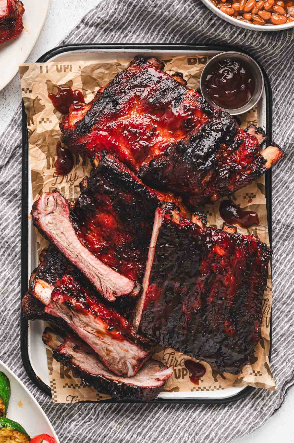 Cooked St. Louis ribs on a baking sheet with BBQ sauce.