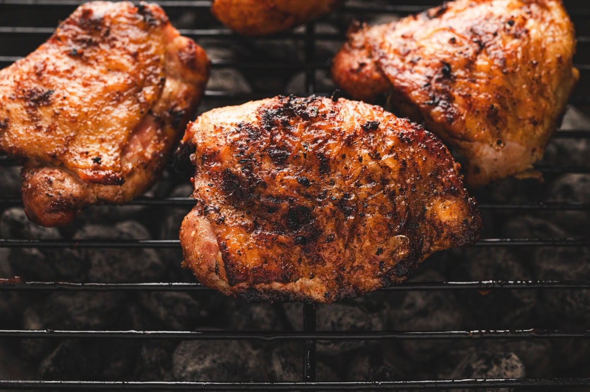 Close up of grilled chicken thighs on a BBQ.