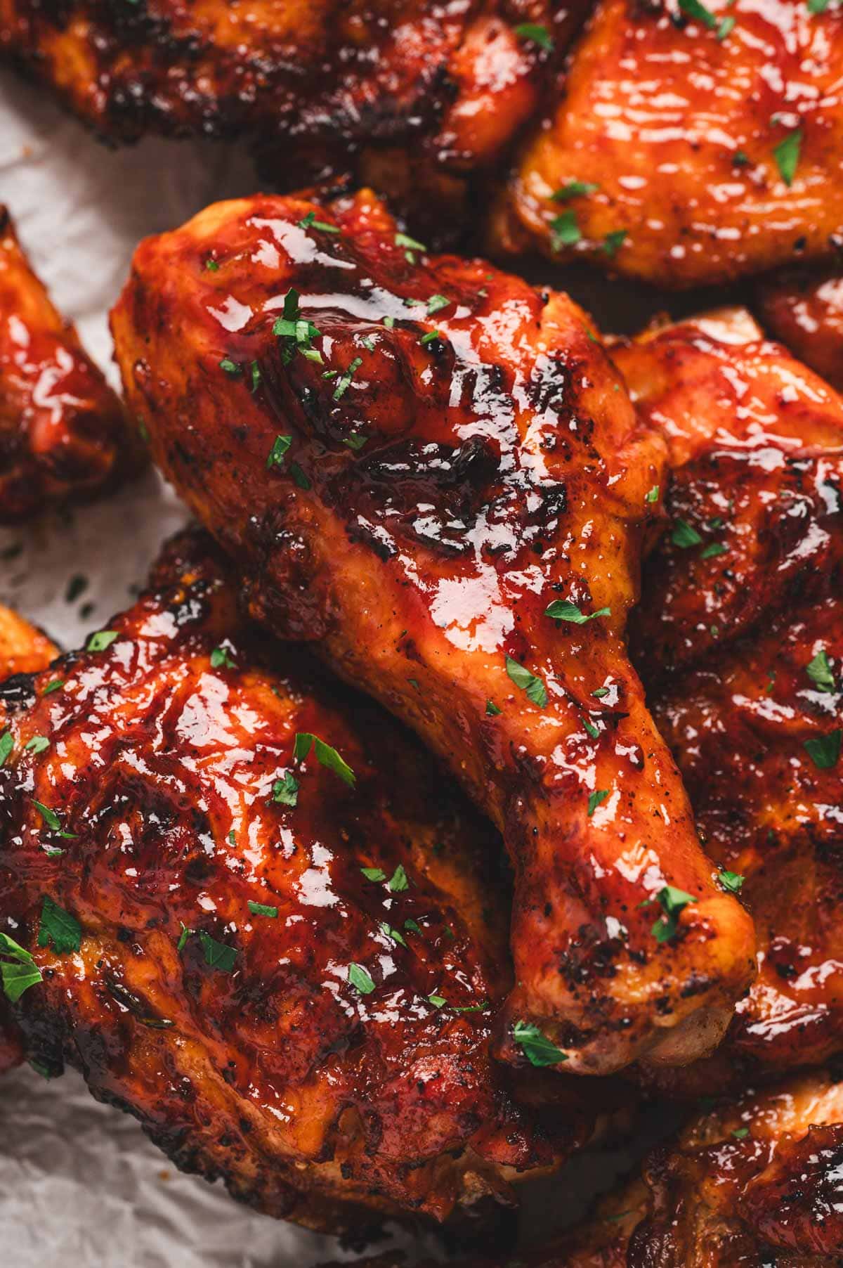 Close up of chicken drumstick drenched in BBQ sauce.
