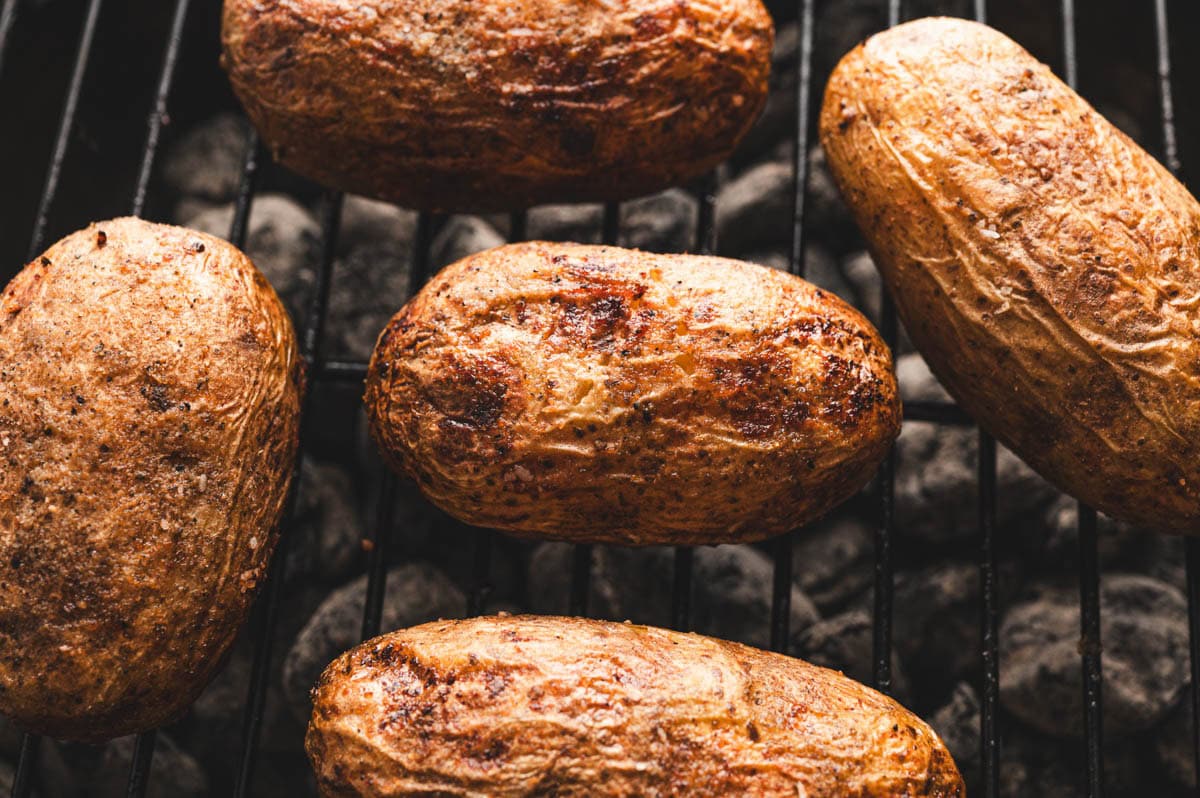 Closeup of potatoes being grilled on a charcoal grill.