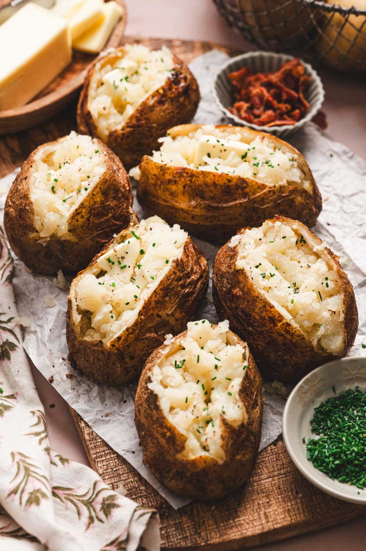 Several baked potatoes on parchment paper.