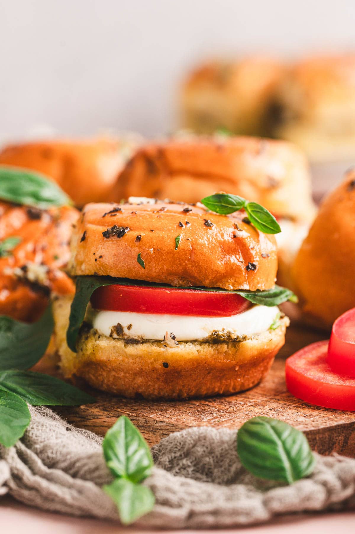 A close-up of a hot caprese slider with fresh basil on top.