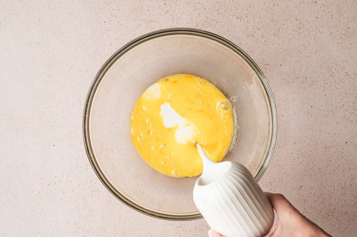 Wet ingredients for buttermilk pancakes being added to a glass bowl.