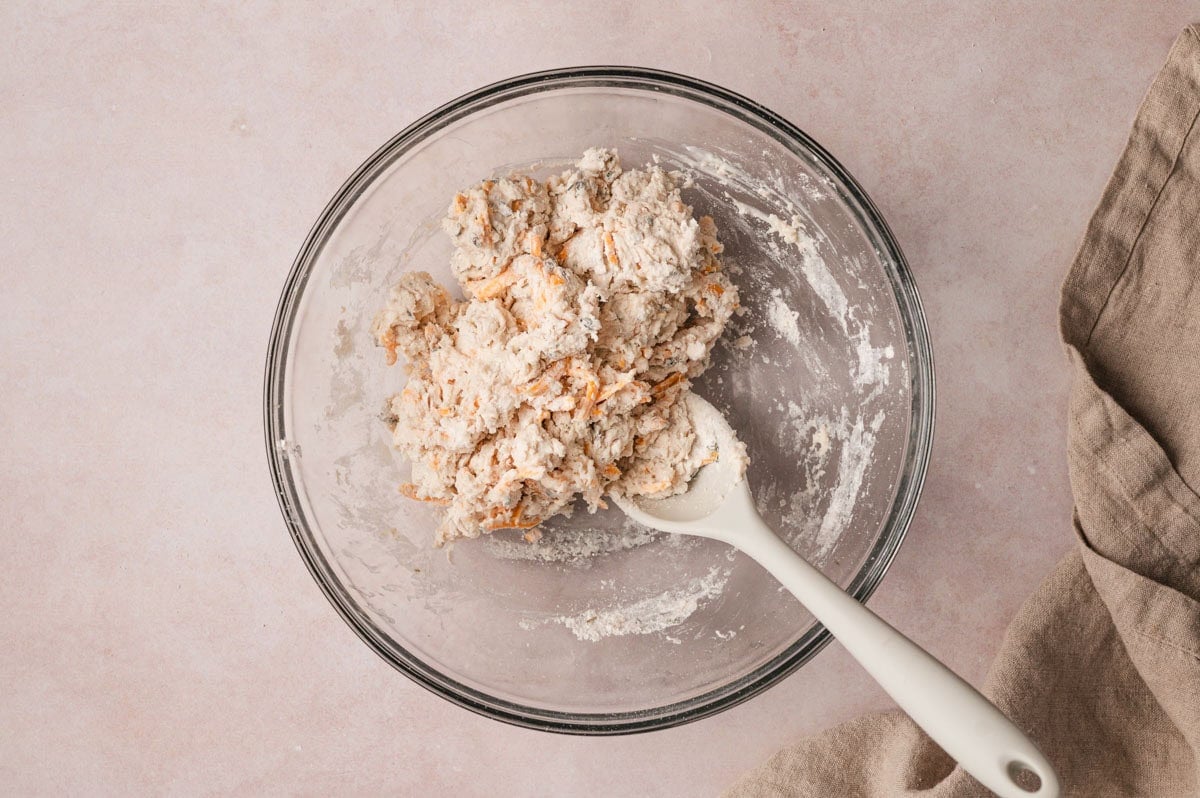 Biscuit dough with cheese and herbs in a glass bowl.