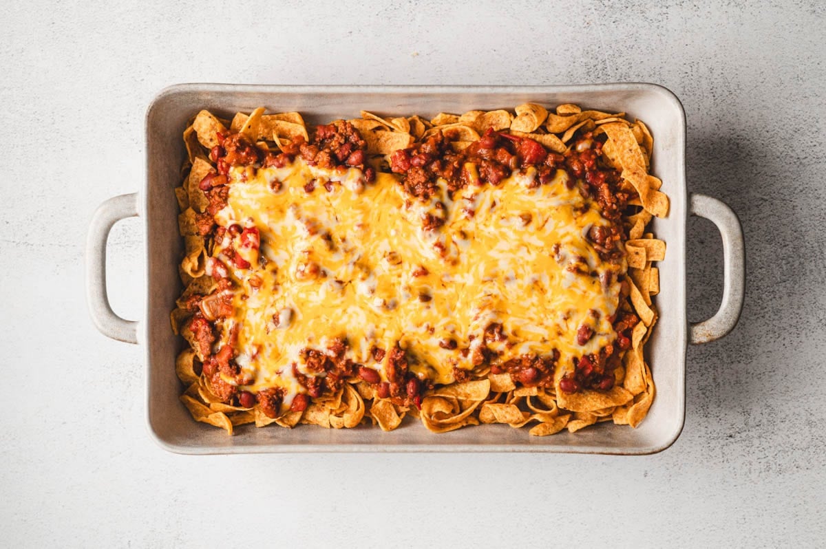 Fritos, chili, and cheese in a casserole dish.