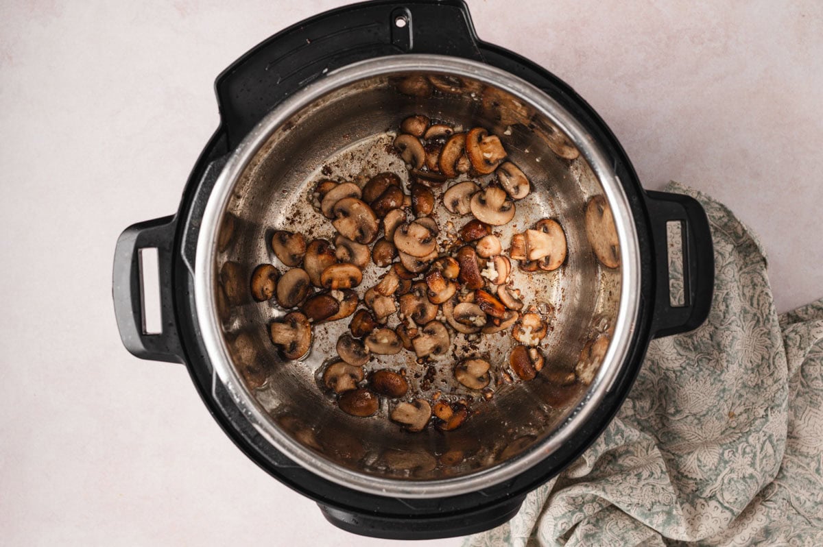 Mushrooms and garlic being cooked in an instant pot.