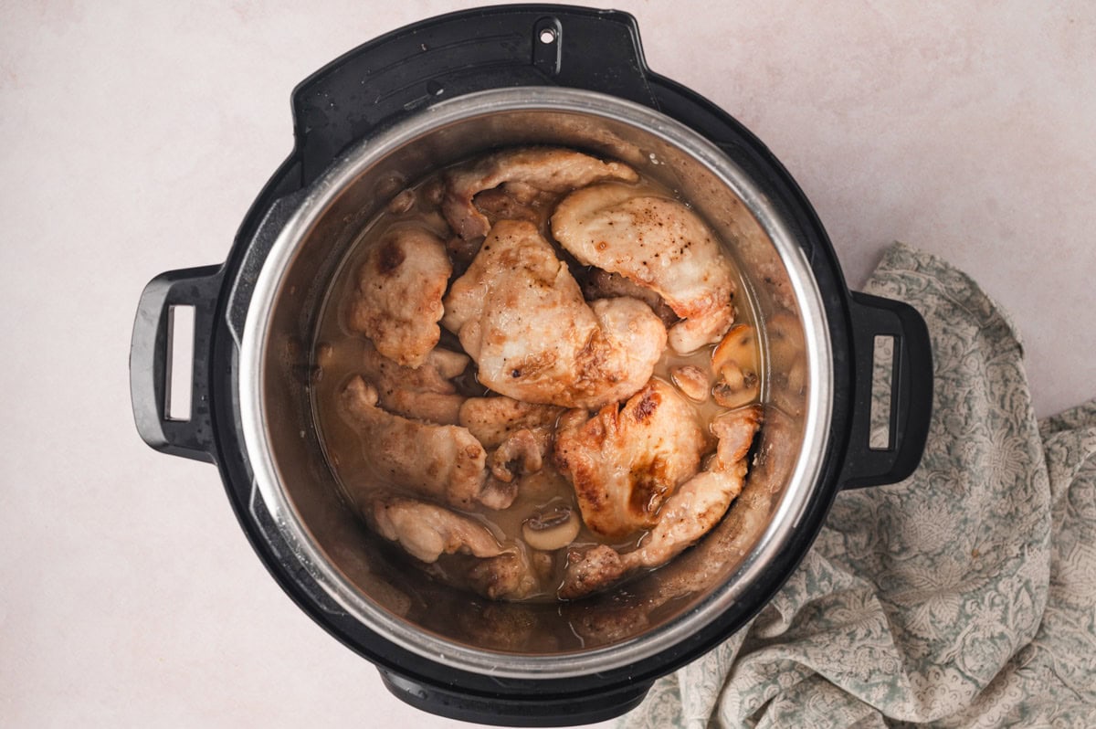Chicken thighs and wine sauce being cooked in an instant pot.