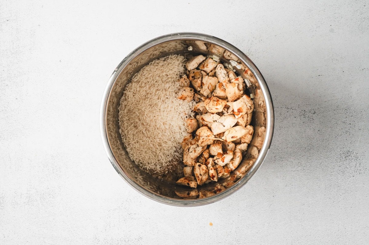 Rice added to the chicken for Instant Pot Chicken and Rice before being cooked.