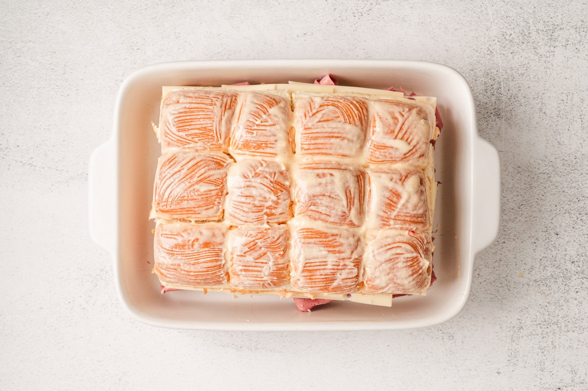 Reuben sliders in a white casserole dish slathered with butter.