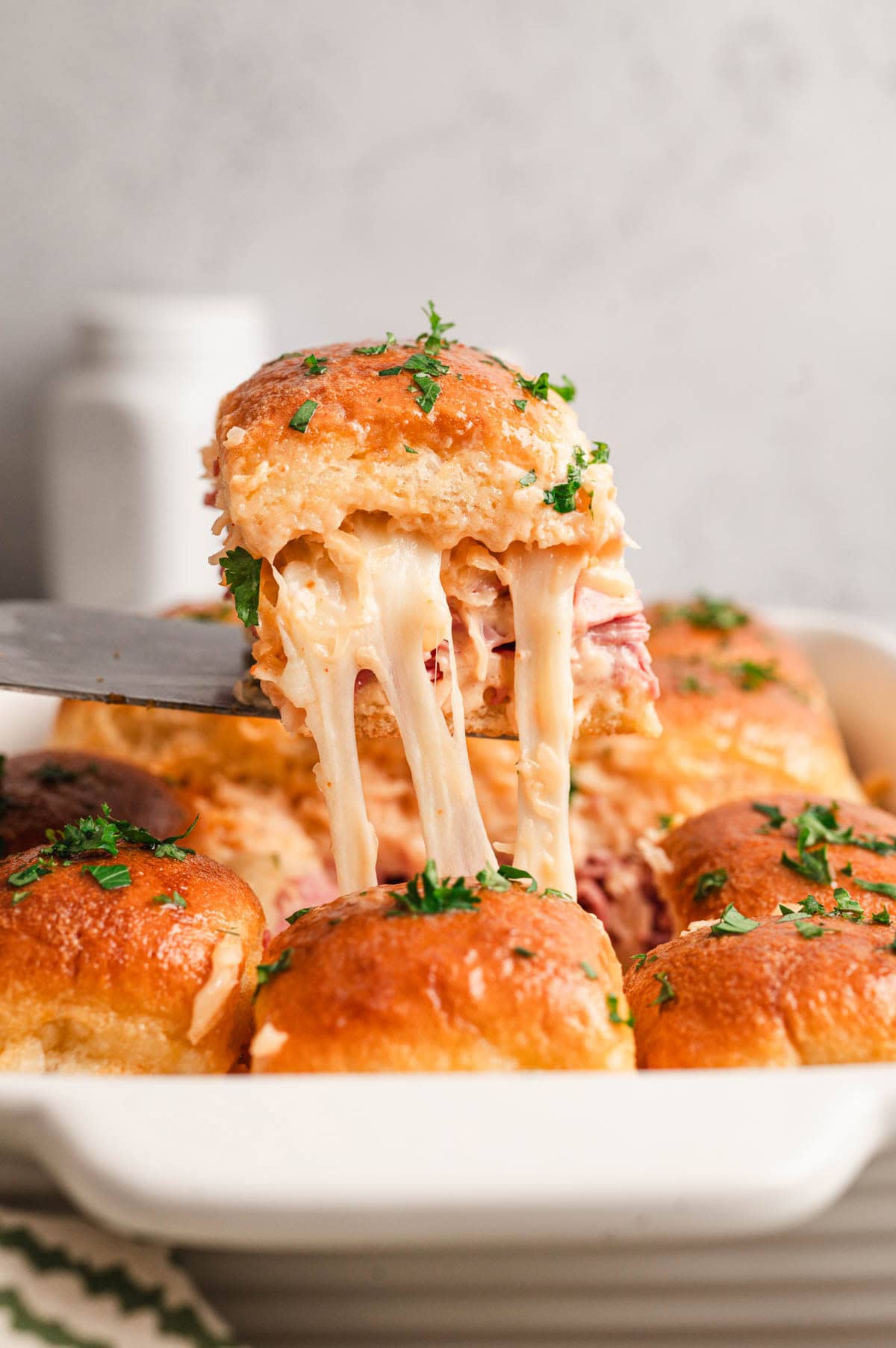 Reuben slider on a spatula with melted cheese and parsley on top.