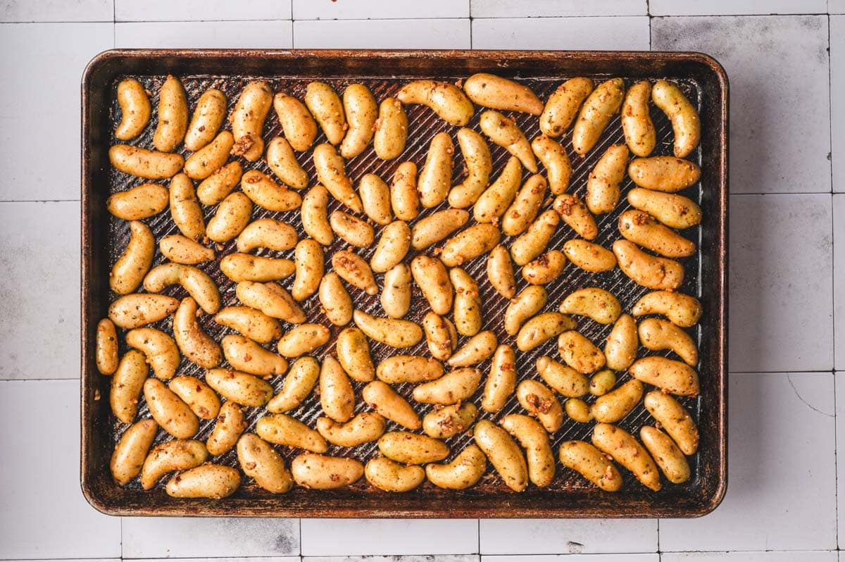 Sheet pan with fingerling potatoes arranged on it, cut side down.