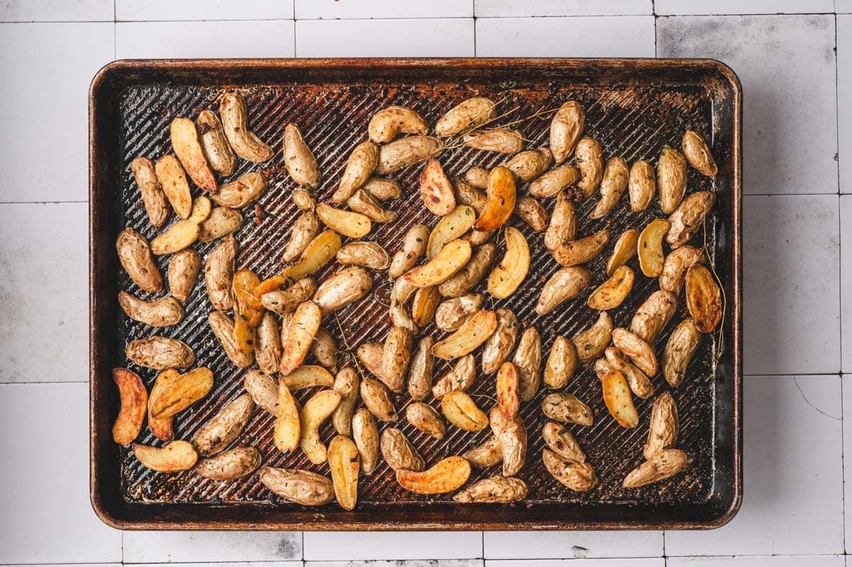 Roasted golden brown fingerling potatoes on a baking sheet.