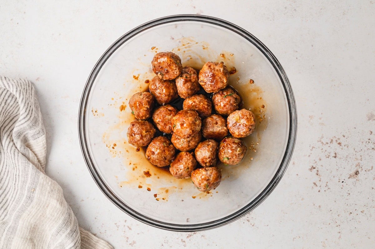 Meatballs in teriyaki sauce in a clear glass bowl.