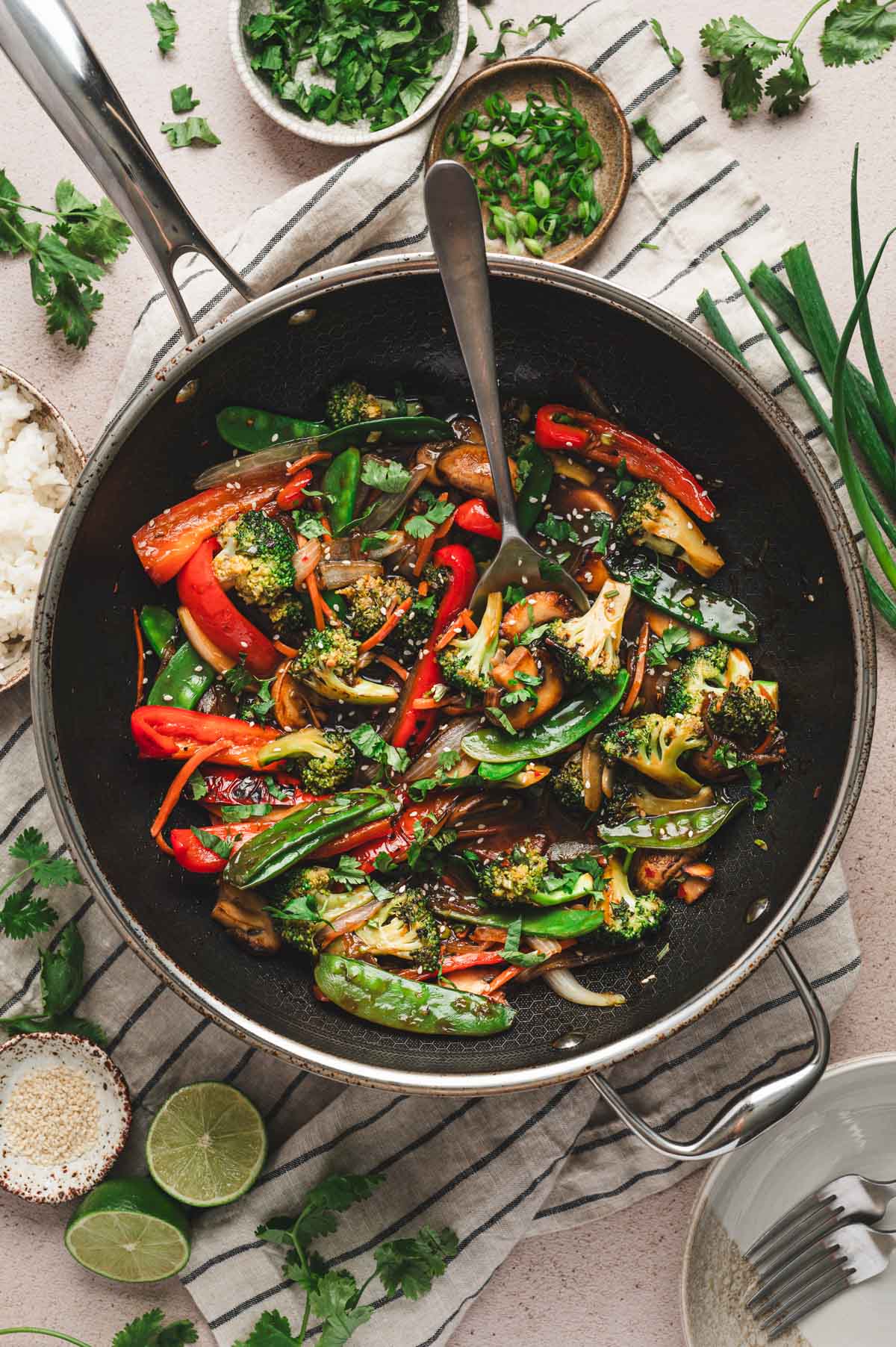 Vegetable stir fry in a skillet with a large serving spoon in the dish.