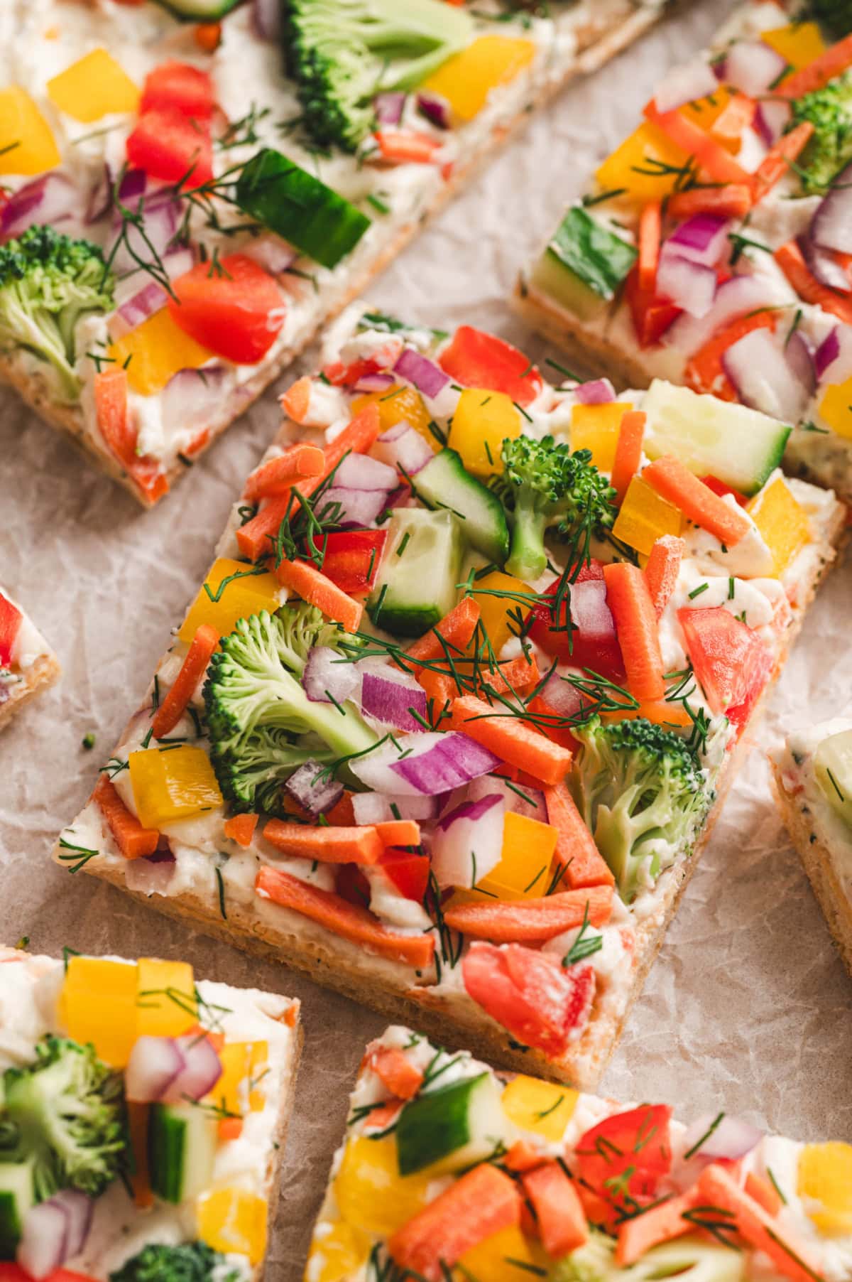 Close up of piece of veggie pizza with fresh veggies and herbs on top.