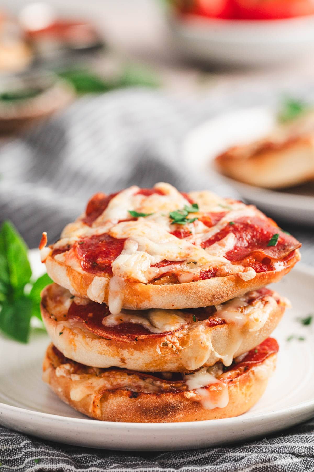Stack of english muffin pizzas on a white plate.