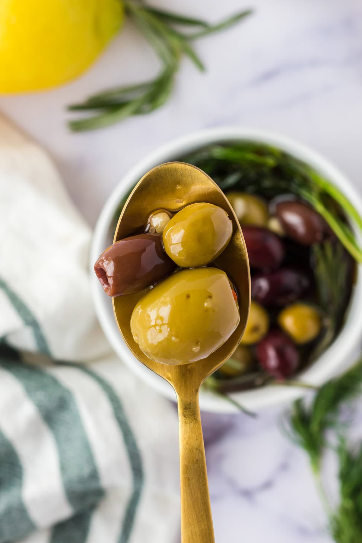 A gold spoon with 3 olives on it.