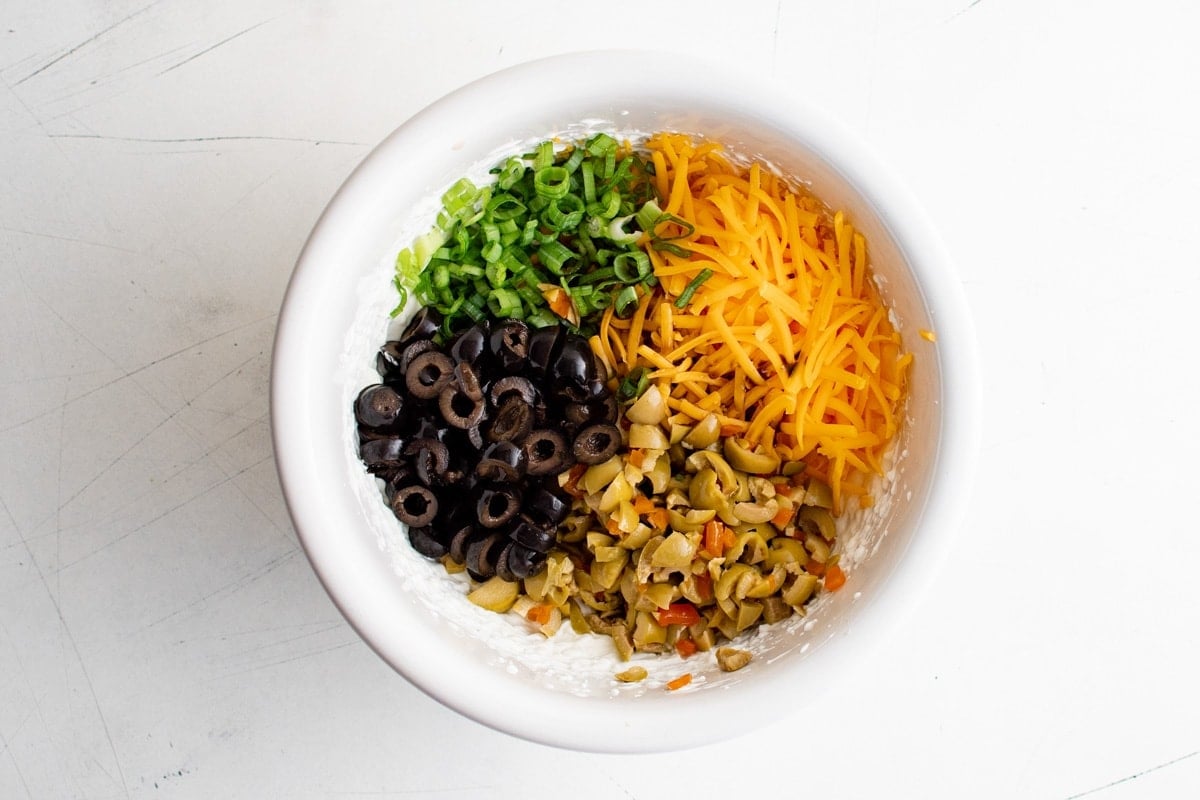 Ingredients for creamy olive dip in a white bowl