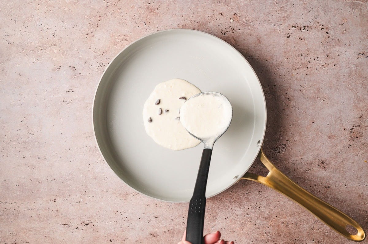 Chocolate chip pancake batter being ladled onto a skillet.
