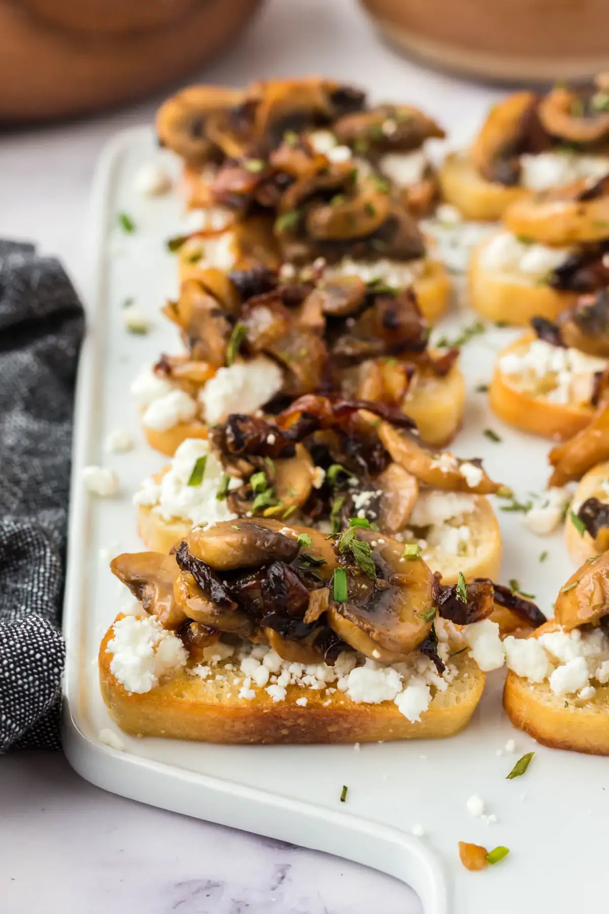 Mushroom Crostini with goat cheese on a white platter.