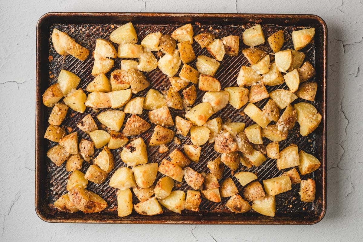 Diced roasted parmesan garlic potatoes on a sheet pan.